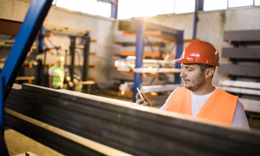 A light touch on the tiller: the secret to happy and engaged employees | A better workplace 3 Manual worker reading a text message on mobile phone in industrial building.