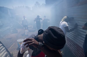 Residents battle to breath in thick smoke as they attempt to salvage belongings as a fire rages through shacks in Masiphumelele