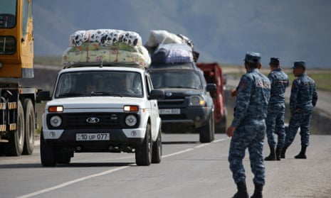 Vehicles carrying refugees arrive watched by soldiers