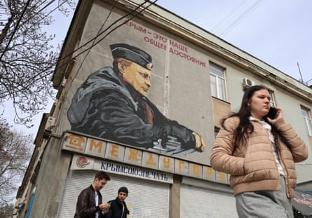 People walk past a mural depicting Vladimir Putin in Simferopol, Crimea.