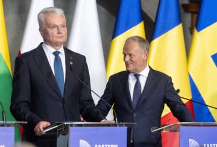 Nausėda and Tusk on stage with a backdrop of flags from participating countries