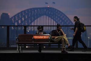 The Sydney Harbour Bridge can be seen while commuters wait for trains