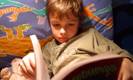 Young boy reading a book in bed at bedtime