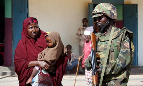 A Somali woman passes an African Union peacekeeper from Uganda.