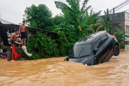 Two youths look at a car surrounded by high floodwaters in Hat Yai in Thailand’s southern Songkhla province on 26 November.