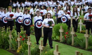 Young people holding flowers and wreaths take part in a memorial ceremony at Thiepval.