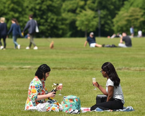 Two women enjoy a drink on the grass in Hyde Park, London