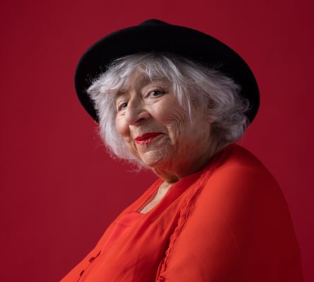 Actor Miriam Margolyes in red dress and black hat, against red background