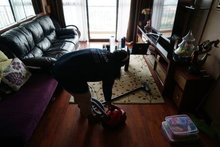 Woman vacuums a living room in Jakarta. 