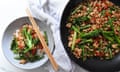 A bowl of Sarah Pound's sticky chicken with Broccolini and green beans sits on a table to the left of the same meal in a wok to the right.