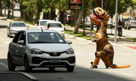 A demonstrator dressed as a dinosaur protests the BTG Pactual Bank, which does business with companies that explore fossil fuels in the Amazon region.
