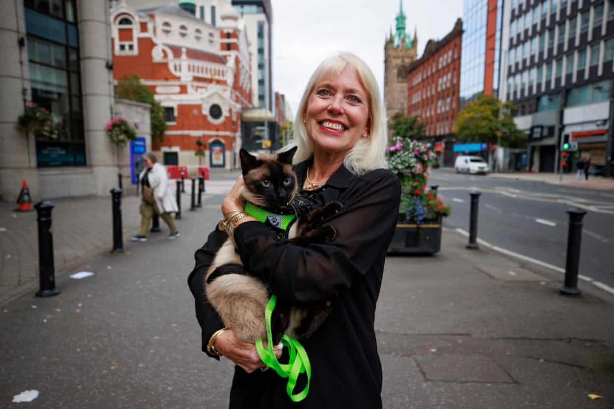 Holly Hennessy smiles holding her Siamese cat Captain on a Belfast street