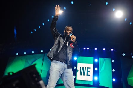 a man performing on stage with an arm raised