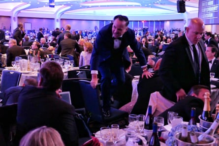 a man climbs on a chair in a crowded room