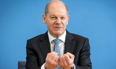 Man in a suit gesturing with his fingers curled up
