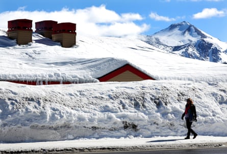 A person walks past a snowbank in front of a restaurant in Mammoth Lakes, California.