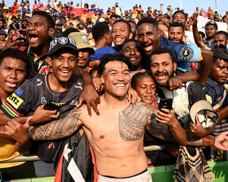 A shirtless Samoan rugby league player poses for photos with excited fans