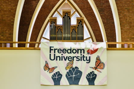 banner says ‘freedom university’ with illustrations of butterflies and raised fists. the banner hangs under an organ