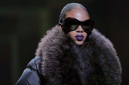 A model wearing a coat with voluminous fur collar and large black sunglasses