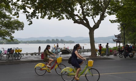 People ride public bike share cycles around Hangzhou’s scenic West Lake.