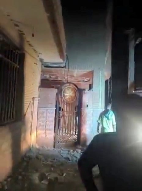 Two men inspect near a door with debris on the ground.