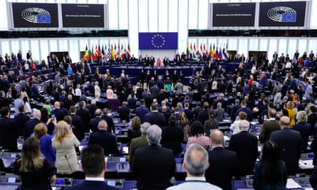 MEPs in the parliament stand looking toward the centre of the room