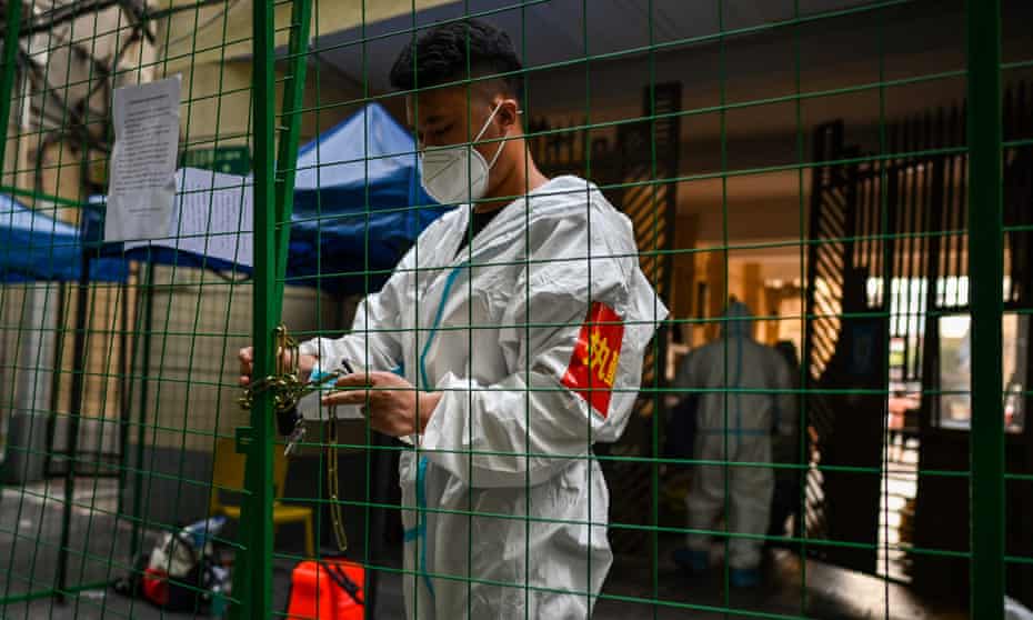 A worker padlocks fencing, securing a residential area under Covid lockdown in the Xuhui district of Shanghai on Wednesday. 