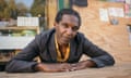 Lemn Sissay seated with his hands resting on the table in front of him