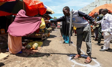 A woman sells fruits to a customer standing in a circle to mark social distance, as a measure to stem the spread of the coronavirus disease at the market centre in Hamarweyne district in Mogadishu, on 16 April.