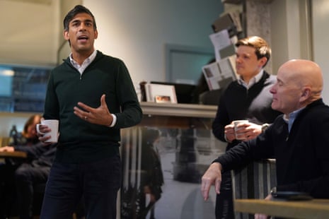 Rishi Sunak speaks as two men look on