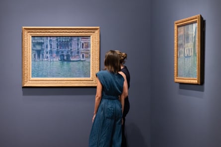 two people stand by paintings on wall at museum
