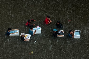 People carry water bottles through floodwater in Bangkok