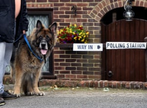 A voter arrives with his dog at a private garage which is being used as a polling station in Coulsdon