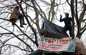 An enforcement agent speaks to an Extinction Rebellion activist sitting in a tree in London, England