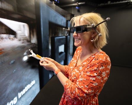 Linda Geddes wearing specialised eye-tracking and motion-sensing goggles smiles while interacting with a large digital display in an immersive research environment.