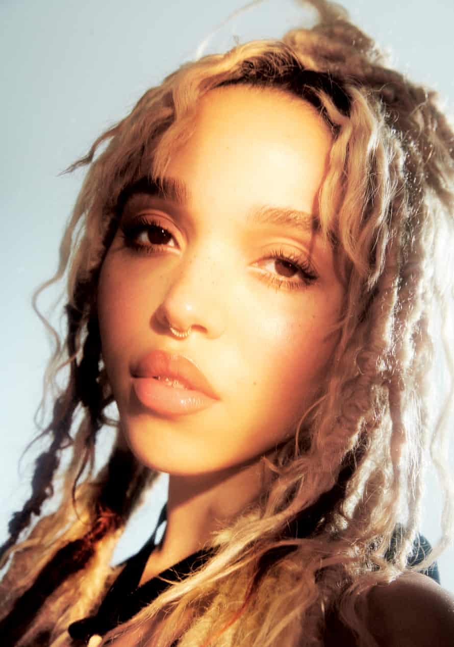 Portrait of FKA twigs with blond hair against a pale blue background