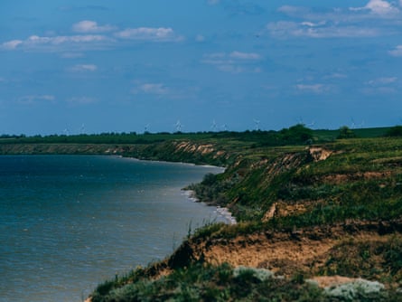 Coastline by the sea, with wind turbines in the distance