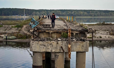 A local resident walks on the destroyed bridge over the Donets river in Staryi Saltiv, east of Kharkiv.
