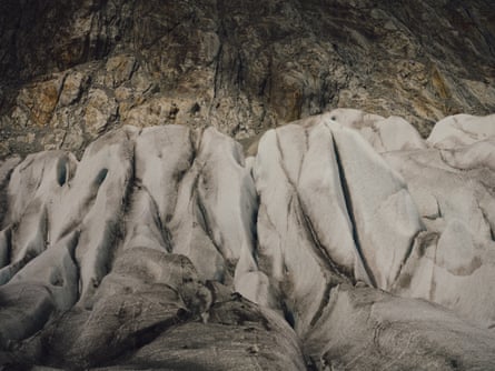 Folds of ice with a sooty crust on a glacier with bare rock above