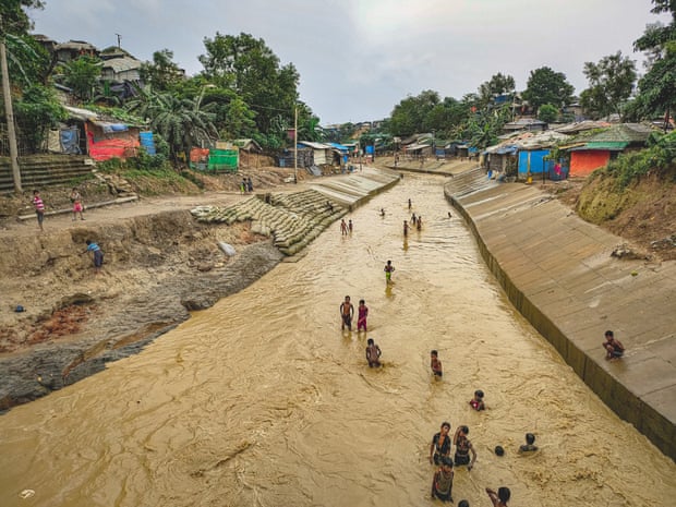 En gruppe rohingya-gutter leker i en vannvei ved siden av tilfluktsrommene deres etter regn