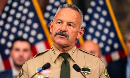 Sheriff Chad Bianco speaks into a pair of microphones