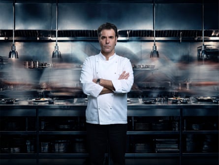 Fernández in a chef’s white coat, his arms folded, standing in a restaurant kitchen and looking into the camera