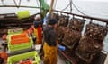 Two fishermen onboard a trawler with nets full of shellfish