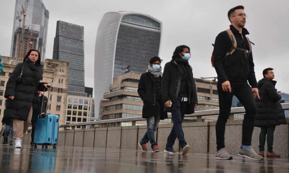 Pedestrians and commuters walk across London Bridge