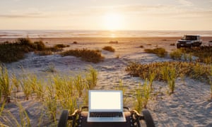 Laptop on deck chair overlooking sunset on beach