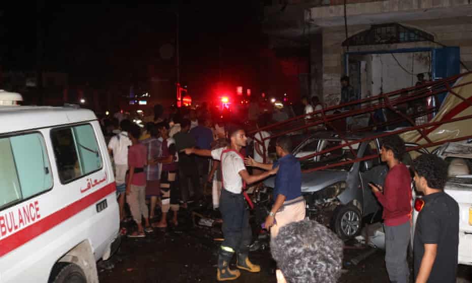 Yemeni emergency service staff and bystanders gather at the site of a blast near Aden airport.
