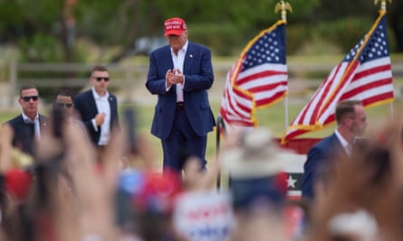 Donald Trump, wearing a red Maga hat, stands on a stage before two American flags in Las Vegas, Nevada.