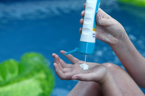 Someone applies sunscreen from a bottle
