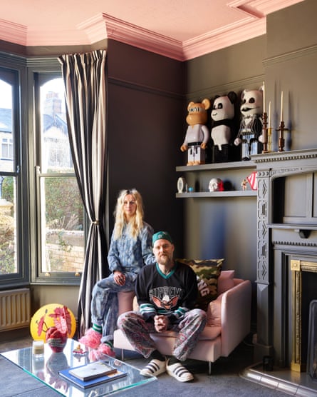 Daisy and Neil in their living room, with its deep-grey walls, pink ceiling and Bearbrick figurines