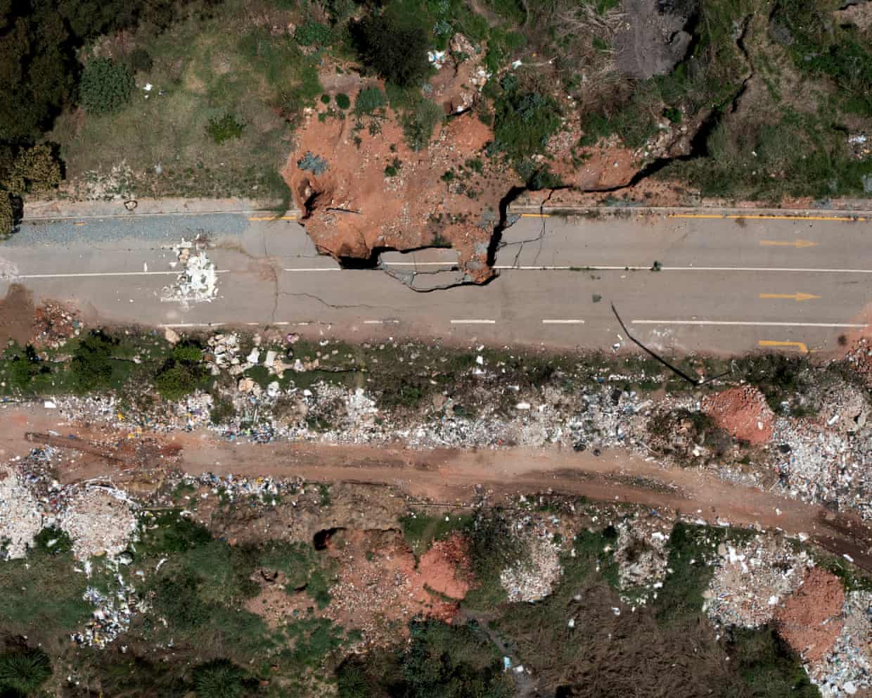 Aerial view of a collapsed, cracked road near Johannesburg, with a sinkhole and scattered debris